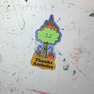 A humorous sticker featuring a tree on fire with a face and the text 'Thanks Assholes,' perfect for those who enjoy witty and satirical stickers.