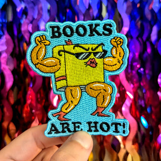 Vibrant iron-on patch showcasing a confident book character with the catchy phrase 'Books are hot!' – ideal for customizing jackets, bags, or jeans with a touch of literary flair!"