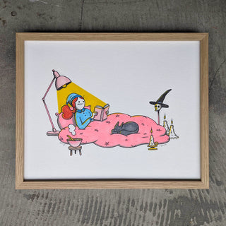 Framed illustration of a person reading a book on a cloud with a witch hat and candles.