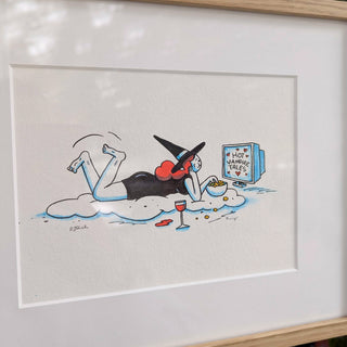 Framed illustration of a woman in a witch hat lying on a cloud, watching TV with a bowl of popcorn.