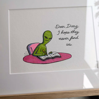 Framed artwork of an alien writing in a diary with text 'Dear Diary, I hope they never find us.'
