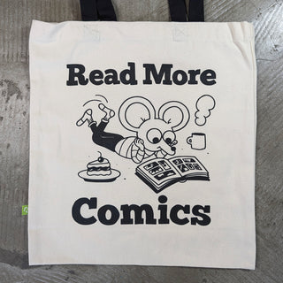 An off-white canvas tote bag with black handles, featuring a black graphic print of a cartoon mouse reading a book with the text 'Read More Comics'.