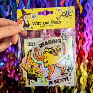 A hand holds a War and Peas holographic sticker pack featuring six absurdist, dark humor designs. The visible sticker shows a muscular book reading a book with the caption "READING IS SEXY!" in bold letters. The pack includes holographic stickers with vibrant colors and surreal motifs, perfect for laptops, water bottles, or journals. Made with love, these unique, hand-drawn stickers are ideal for fans of quirky, conversation-starting art and offbeat gifts.