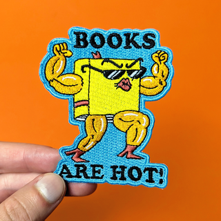 Patch with cartoon book character flexing muscles and text 'BOOKS ARE HOT!' held against an orange background.